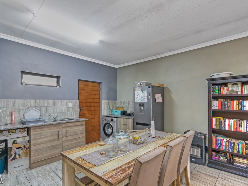 A functional kitchen area featuring wood-look cabinetry, tiled backsplash, and integrated laundry plumbing, with visible ceiling wear requiring maintenance.