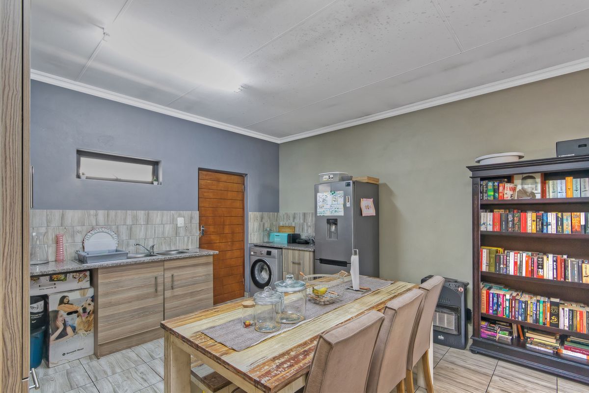 A functional kitchen area featuring wood-look cabinetry, tiled backsplash, and integrated laundry plumbing, with visible ceiling wear requiring maintenance.