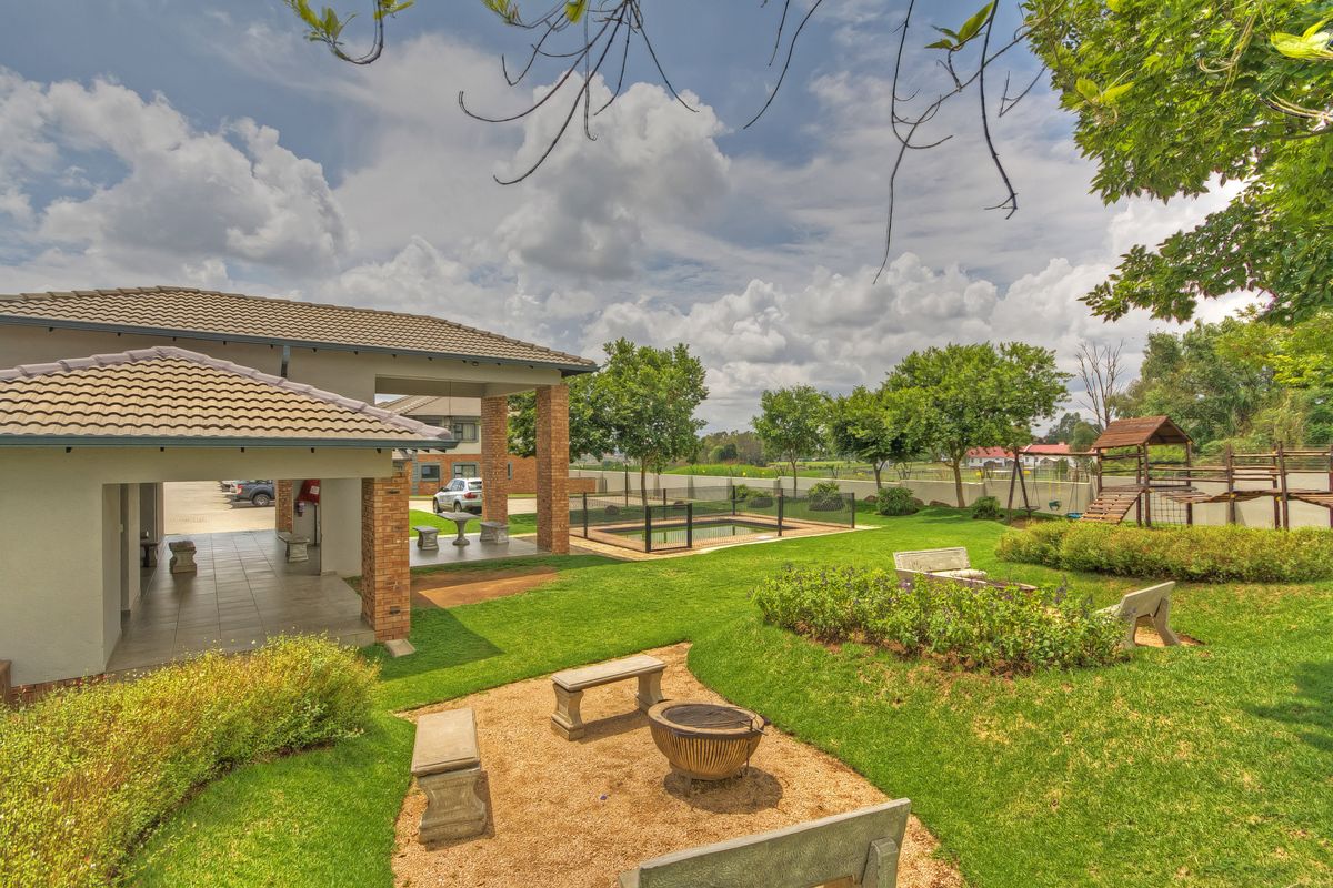 Spacious rear garden featuring a covered patio, swimming pool with safety fencing, and well-maintained lawn and landscaping.