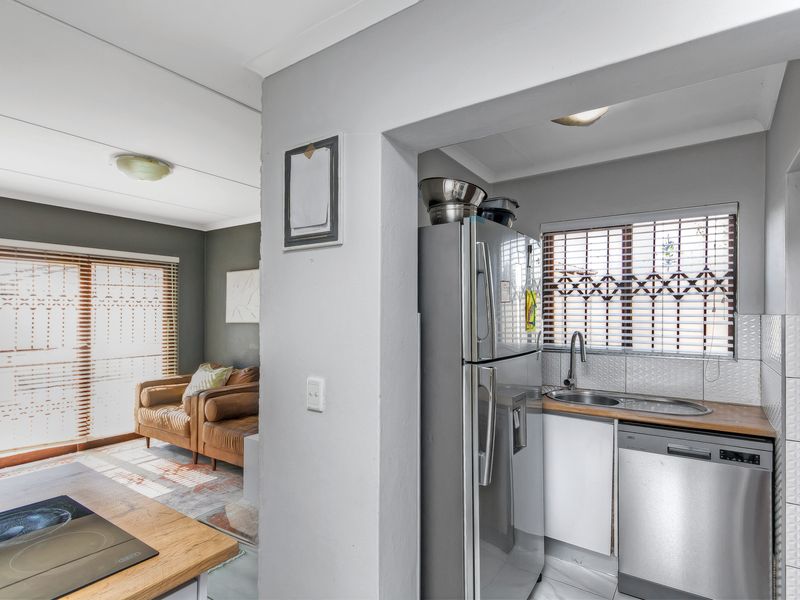 A compact scullery area featuring a stainless steel sink, timber countertops, and tiled splashbacks, conveniently positioned adjacent to the main living space.