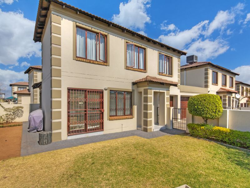 A well-maintained double-story townhouse featuring a paved entrance, secure window gates, and a neat front garden area.