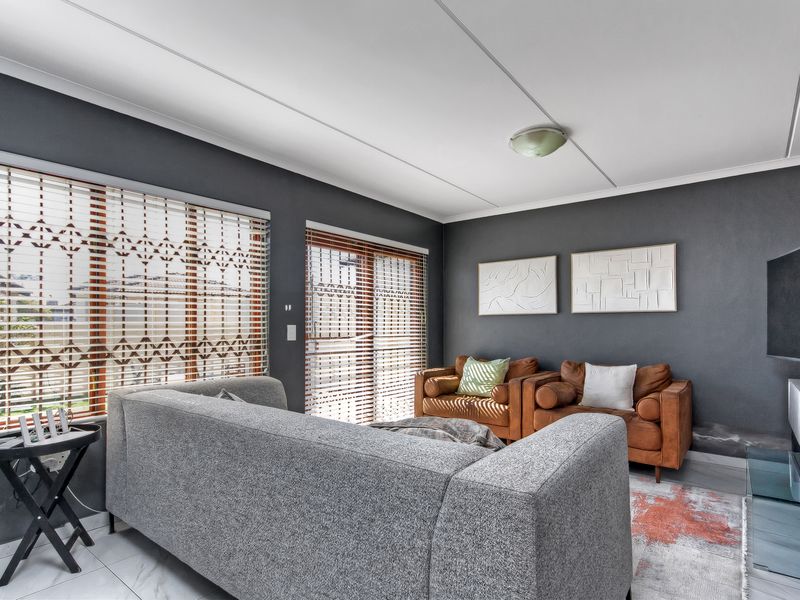 A living room featuring tiled flooring, sliding door access, and venetian blinds, with visible wall staining near the base.