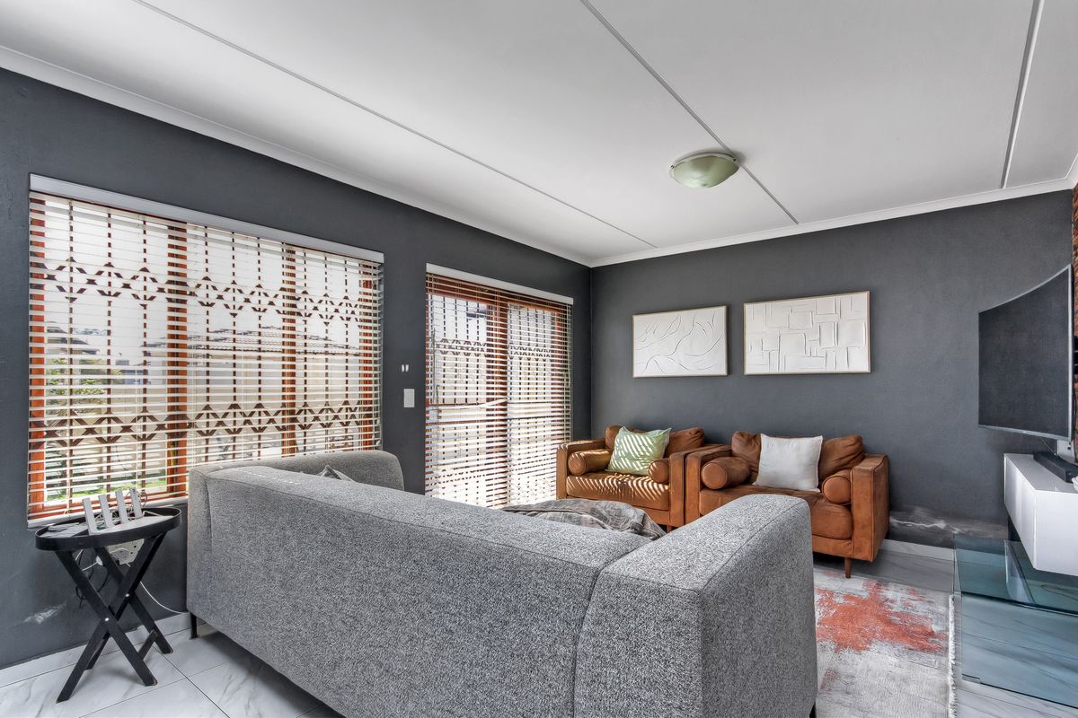 A living room featuring tiled flooring, sliding door access, and venetian blinds, with visible wall staining near the base.
