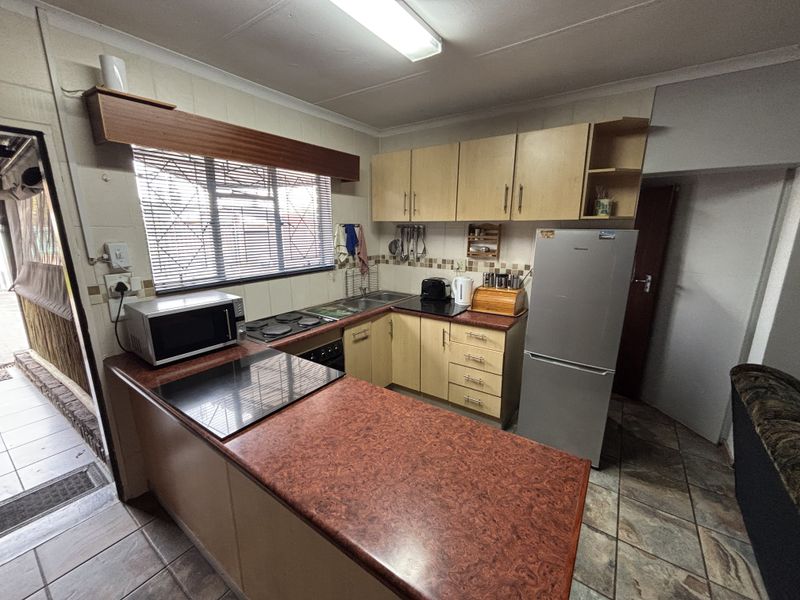 Functional kitchen featuring laminate cabinetry, tiled backsplash, built-in hob and oven, and tiled flooring, offering a practical layout for daily use.