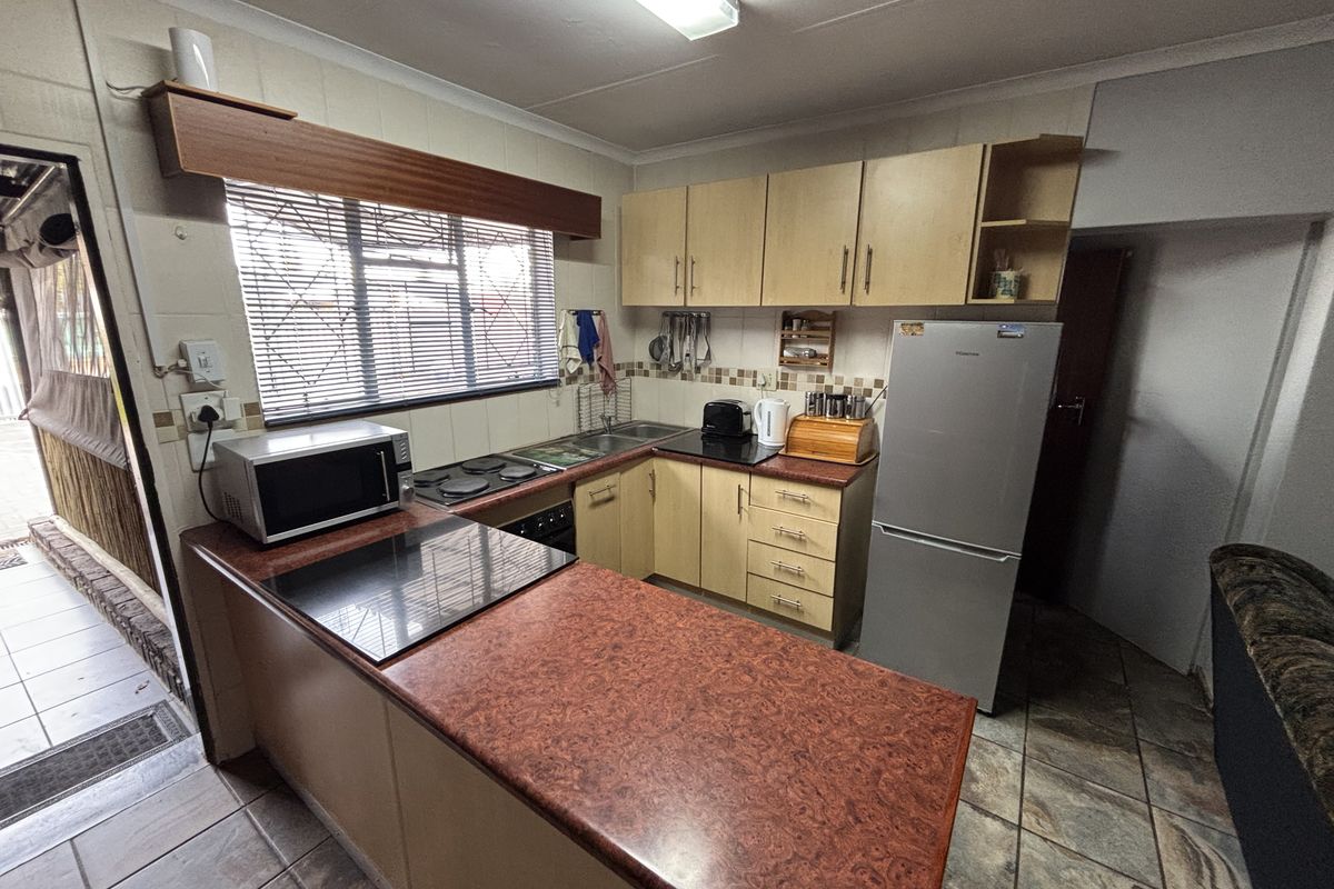 Functional kitchen featuring laminate cabinetry, built-in hob and oven, tiled backsplash, and durable tiled flooring with direct access to an outdoor area.