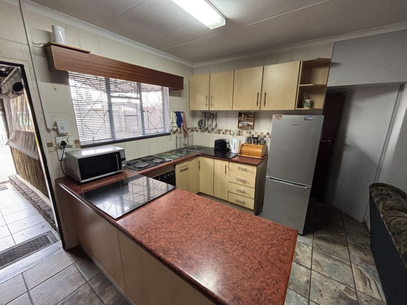 Functional kitchen featuring laminate cabinetry, built-in hob and oven, tiled backsplash, and durable tiled flooring with direct access to an outdoor area.
