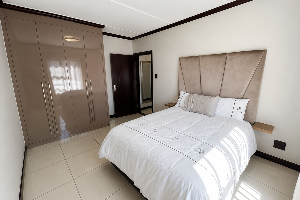 A well-maintained bedroom featuring large format floor tiles, a high-gloss built-in wardrobe, and a neutral color palette.