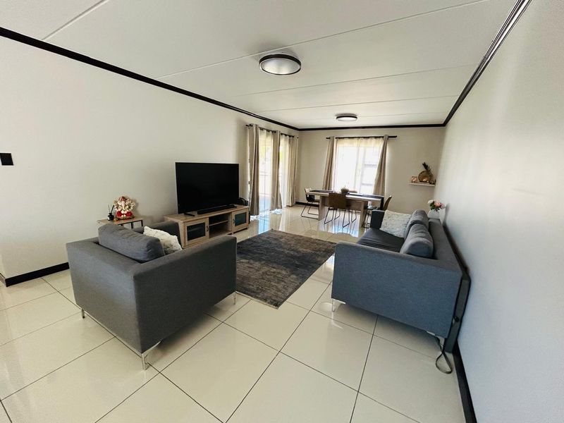 Spacious open-plan living and dining area featuring large format floor tiles, neutral walls, and sliding glass doors providing natural light.