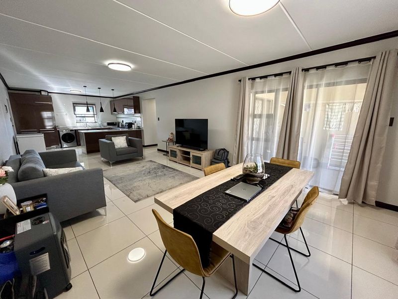 Spacious open-plan living and dining area featuring modern tiled flooring, integrated kitchen cabinetry, and large sliding glass doors leading to an outdoor space.