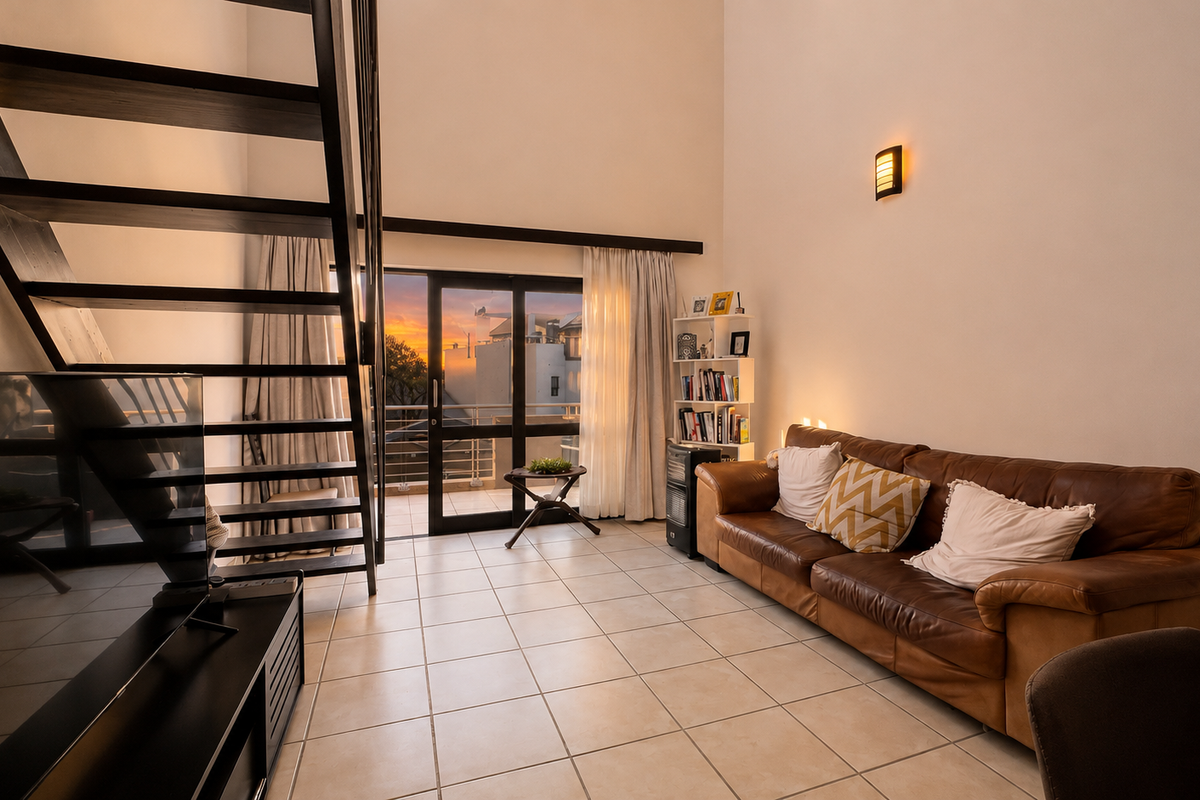 A spacious living room featuring high ceilings, tiled flooring, and a modern staircase leading to an upper level, with access to a balcony.