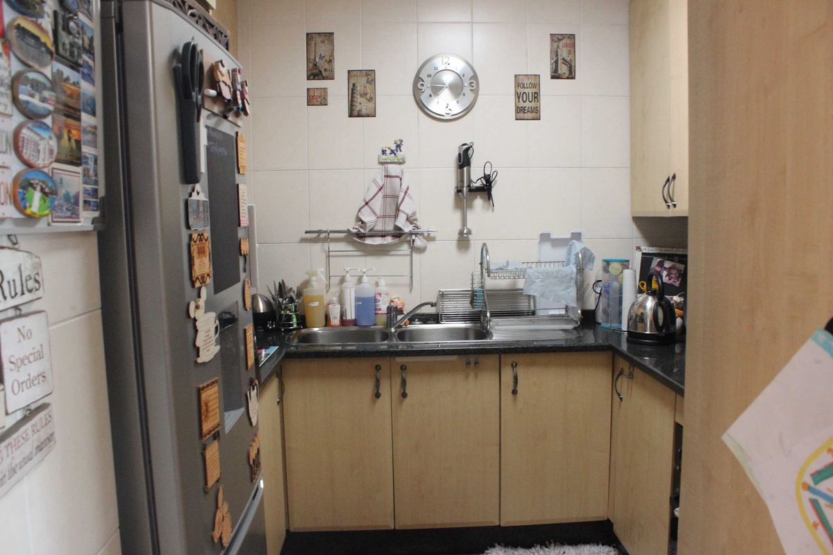 Compact kitchen featuring light wood-tone cabinetry, granite countertops, and a double stainless steel sink with tiled splashback.