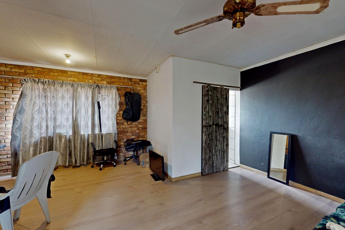 Living room featuring laminate flooring, an exposed brick feature wall, and a sliding barn door, offering a rustic aesthetic with potential for modern updates.