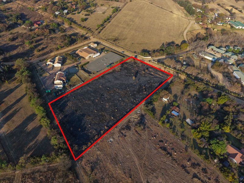 Aerial view of a vacant residential plot with clear boundary markings, situated in a semi-rural residential area.