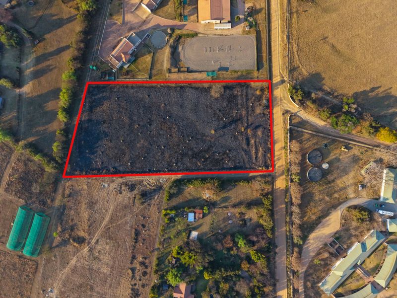 Aerial view of a vacant residential plot with clear boundary markings, situated in a rural or semi-rural estate setting.