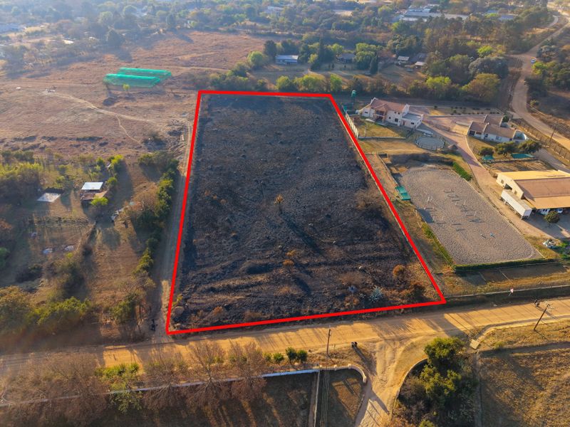 Aerial view of a rectangular vacant residential plot with perimeter fencing, showing signs of recent vegetation clearing or fire.