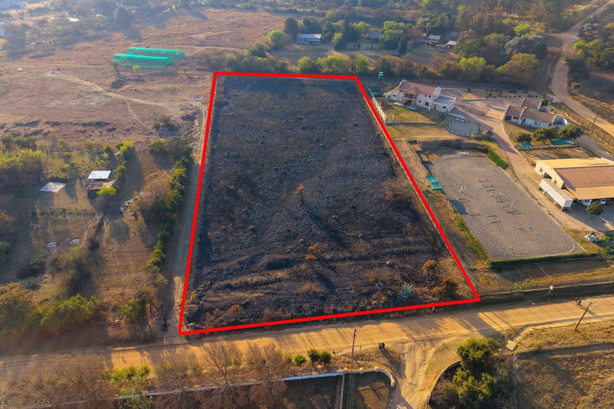 Aerial view of a rectangular vacant residential plot with perimeter fencing, showing signs of recent vegetation clearing or fire.