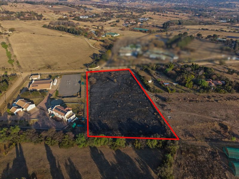Aerial view of a vacant residential plot with clear boundary markings, situated in a semi-rural estate setting.