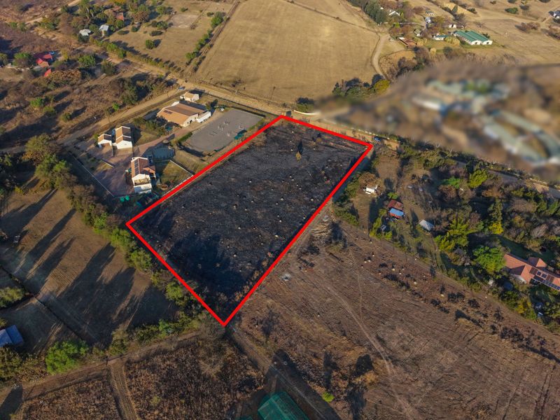 Aerial view of a vacant residential plot outlined in red, situated in a rural or semi-rural landscape.