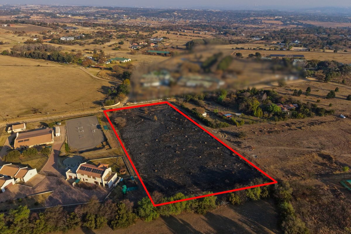 Aerial view of a vacant residential plot outlined in red, situated in a semi-rural landscape with surrounding properties.
