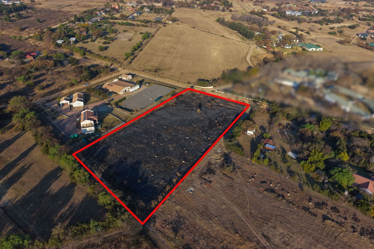 Aerial view of a vacant residential plot outlined in red, situated in a rural estate setting with surrounding vegetation.