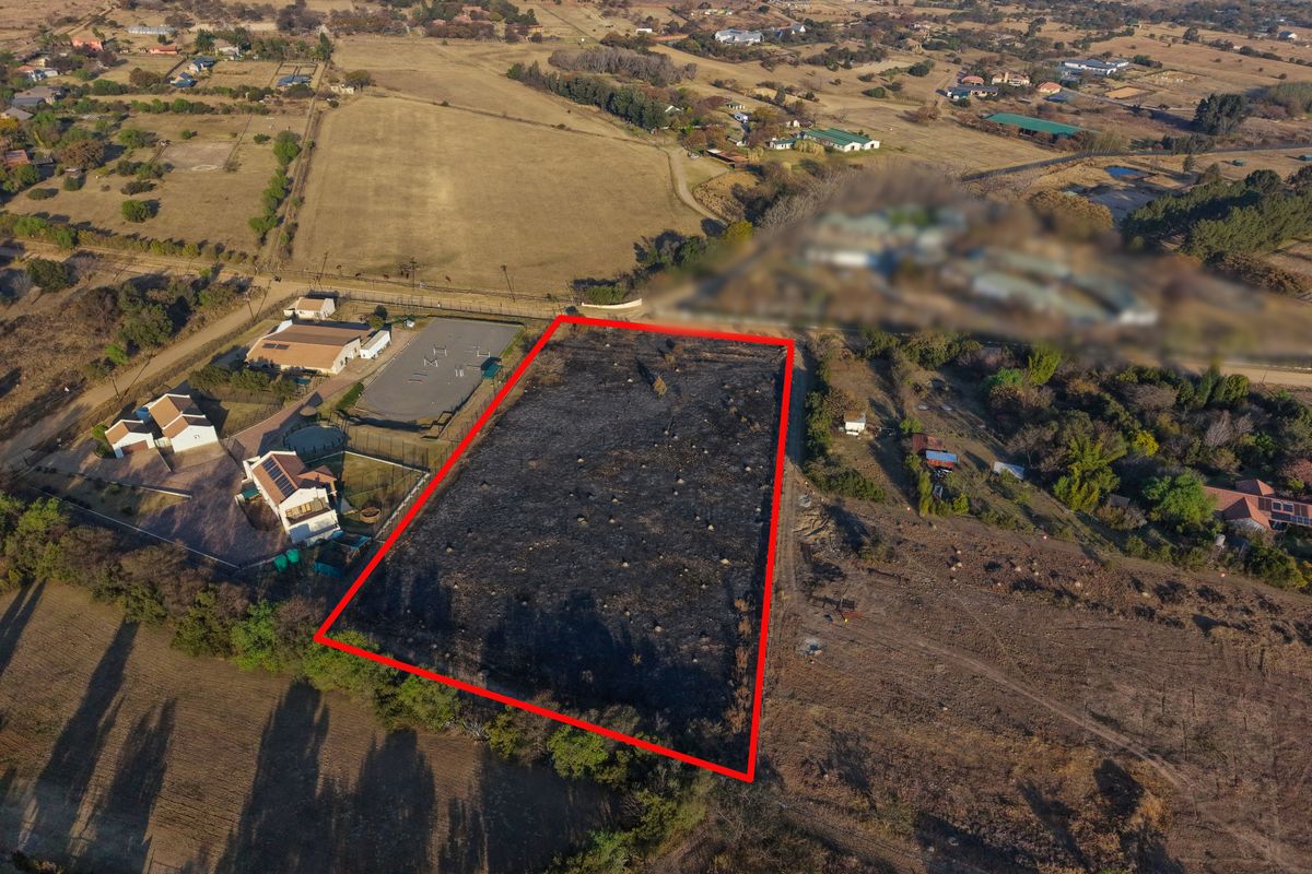 Aerial view of a vacant residential plot with red boundary lines indicating the property perimeter in a rural setting.