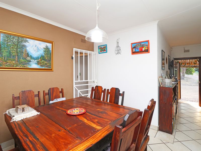 A dining room area featuring tiled flooring, a central pendant light, and a security gate leading to the exterior.