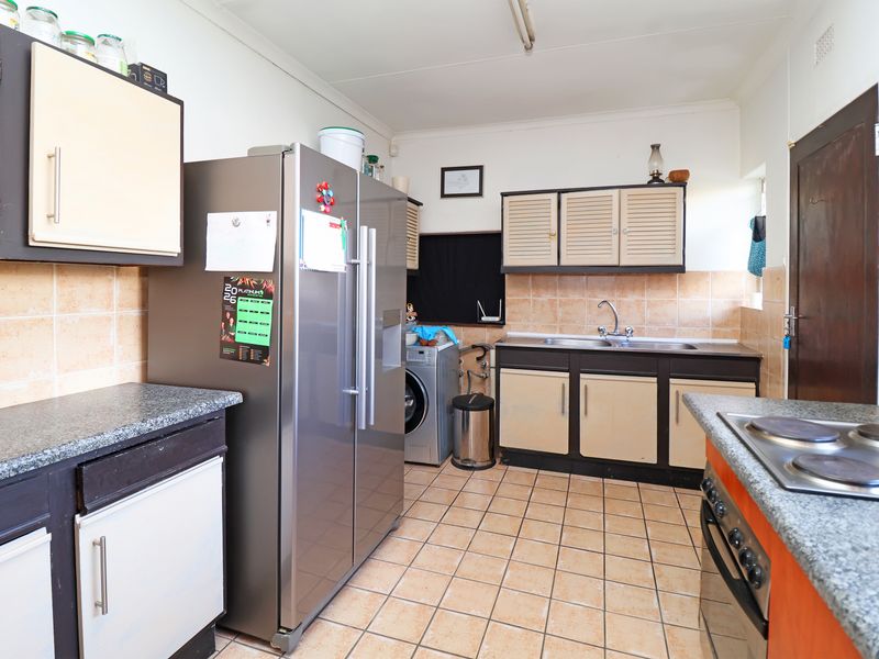 Functional kitchen featuring built-in cabinetry, tiled backsplash, integrated oven and hob, and dedicated laundry plumbing connections.