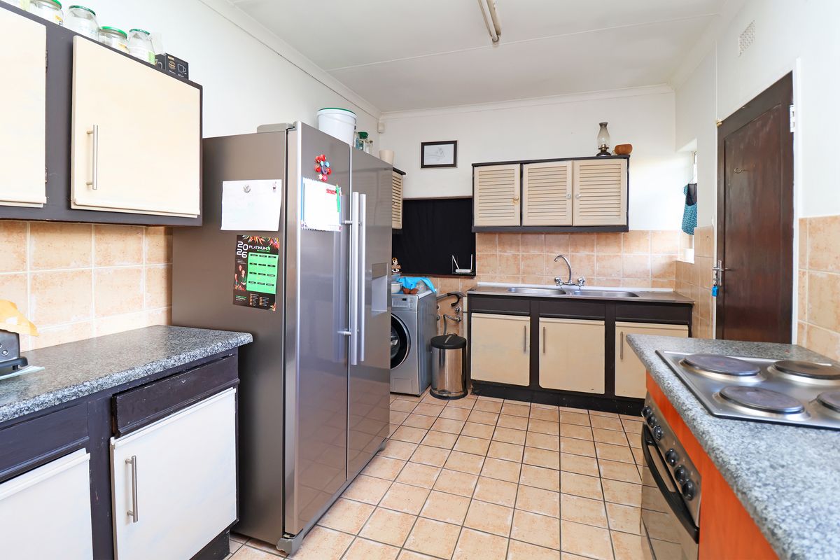 Functional kitchen featuring built-in cabinetry, tiled backsplash, integrated oven and hob, and dedicated laundry plumbing connections.