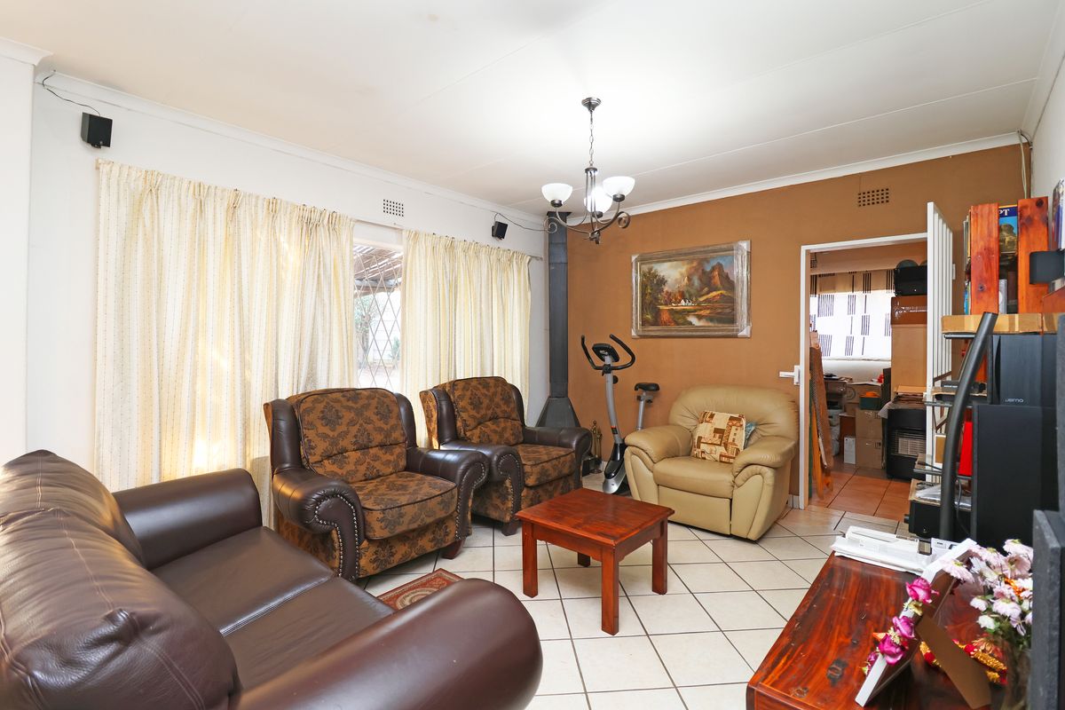 A living room featuring ceramic floor tiles, a coved ceiling, and a freestanding fireplace, providing a functional and comfortable living space.