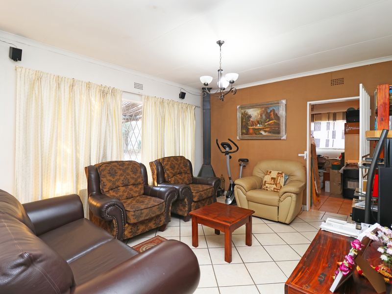 A living room featuring ceramic floor tiles, a coved ceiling, and a freestanding fireplace, providing a functional and comfortable living space.