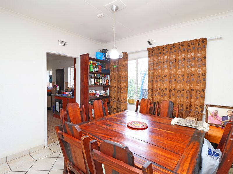 A dining room featuring tiled flooring and a pendant light, with an open doorway leading into the kitchen area.
