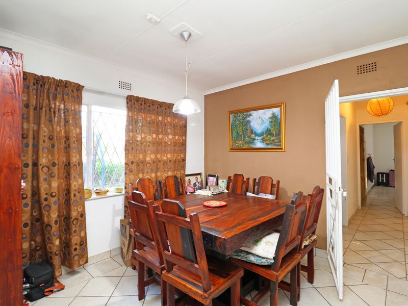 Dining room featuring tiled flooring, a central pendant light, and a security gate leading to the hallway.