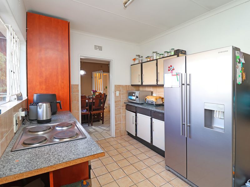 Functional kitchen featuring laminate countertops, electric hob, tiled backsplash, and ample built-in cabinetry with direct access to the dining area.
