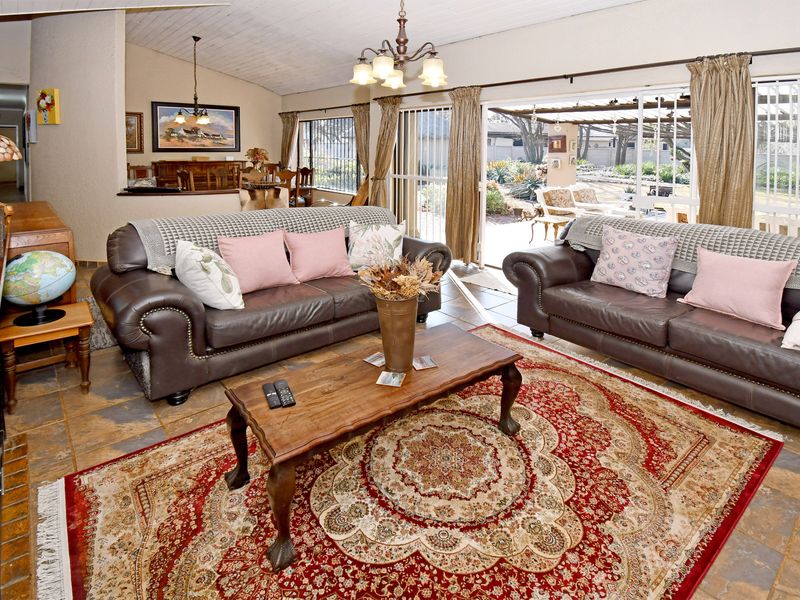 Spacious living room featuring stone tile flooring, vaulted ceilings with exposed beams, and large sliding glass doors providing direct access to the outdoor patio area.