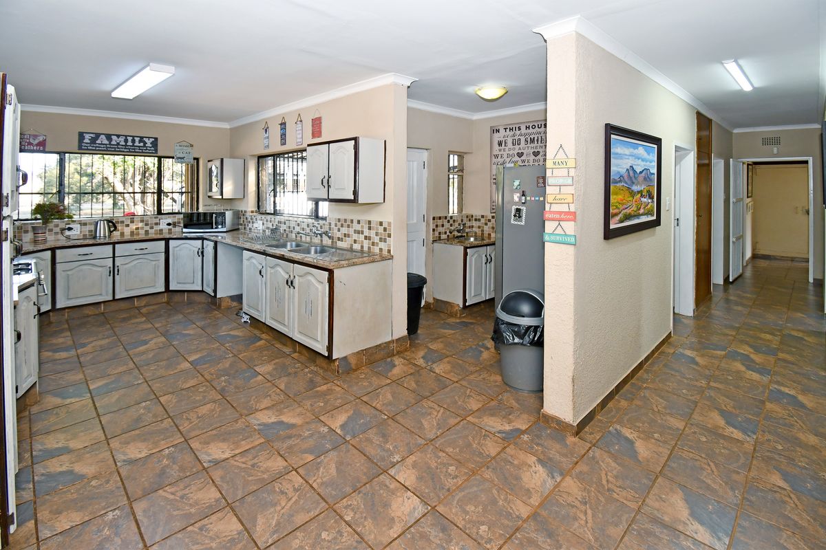 Spacious kitchen featuring tiled flooring, ample built-in cabinetry, double basin sink, and a tiled backsplash, offering a functional layout with adjacent scullery area.