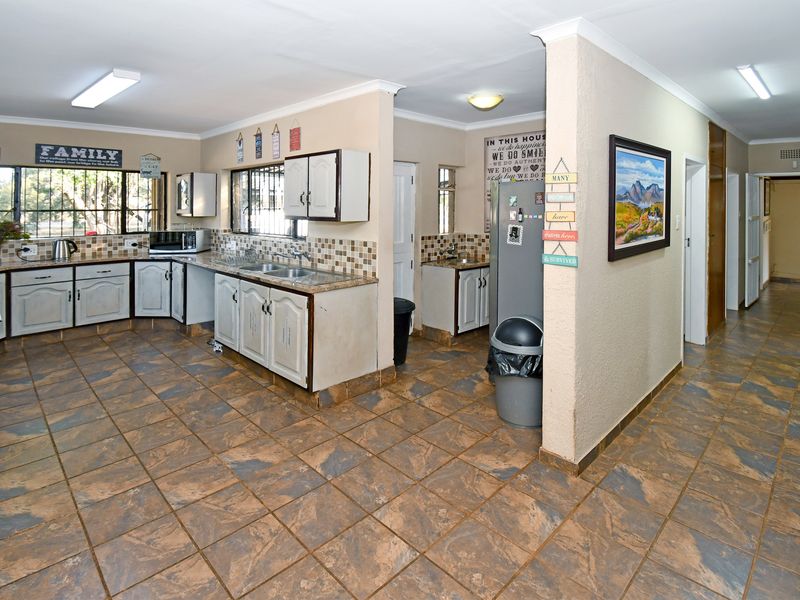 Spacious kitchen featuring tiled flooring, ample built-in cabinetry, double basin sink, and a tiled backsplash, offering a functional layout with adjacent scullery area.