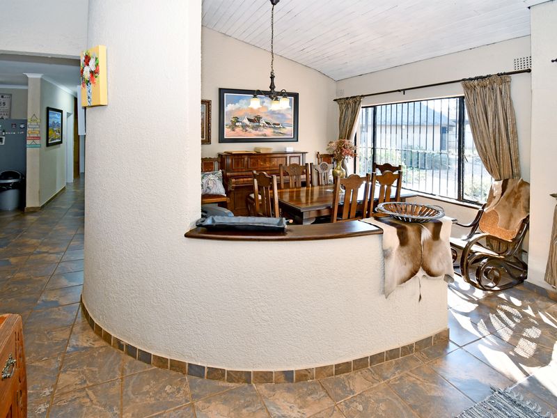 Open-plan living and dining area featuring tiled flooring, a distinctive curved partition wall, and a timber-clad ceiling with natural light.