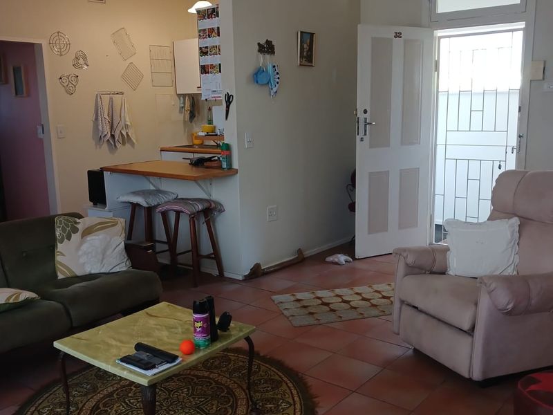Open plan living area featuring tiled flooring and a breakfast counter, with direct access to the exterior through a security gate.