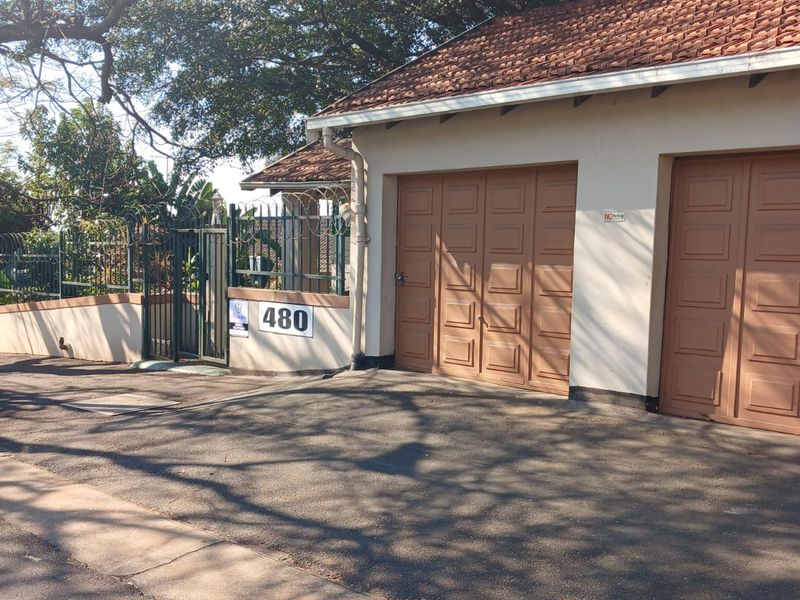 Front exterior view of the property featuring a double garage, tiled roof, and secure perimeter fencing with a gated entrance.