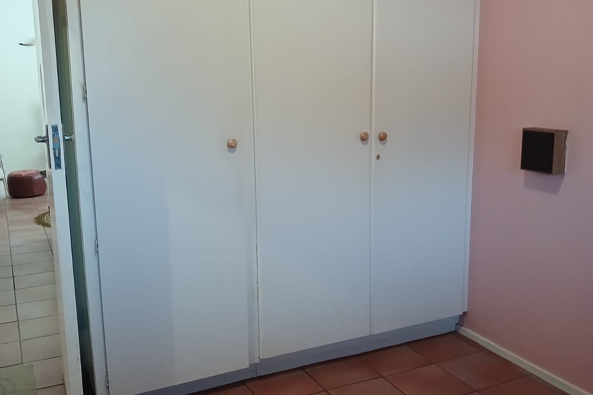 A bedroom featuring built-in cupboards and tiled flooring, offering a blank canvas for potential renovation or restyling.