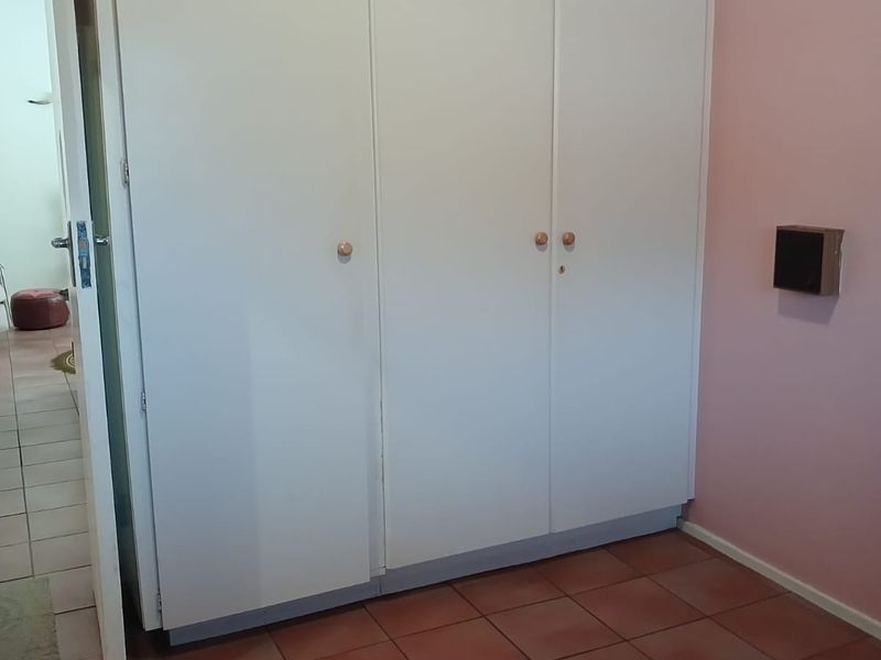 A bedroom featuring built-in cupboards and tiled flooring, offering a blank canvas for potential renovation or restyling.