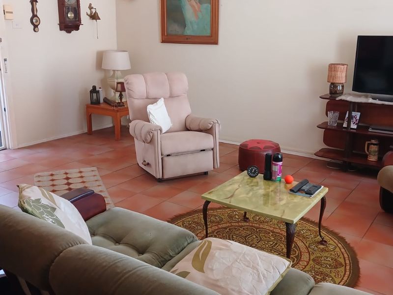 A living room featuring terracotta floor tiles and a ceiling fan, offering a functional space with potential for modern updates.