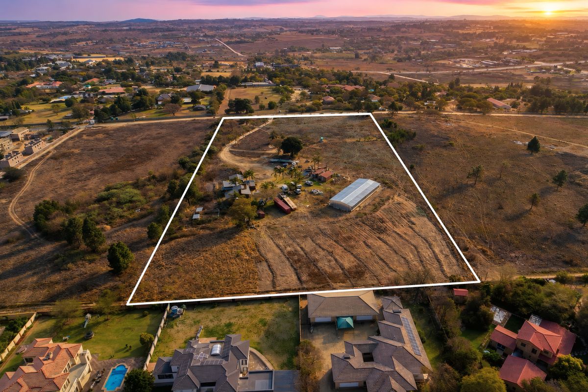 Aerial view of a large residential vacant land plot featuring an existing metal shed, mature trees, and established access paths in a semi-rural setting.