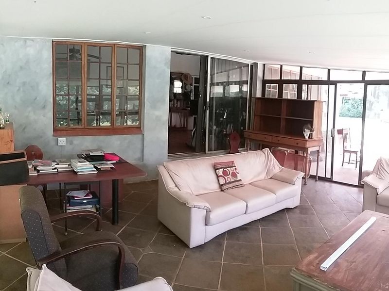 A spacious enclosed patio featuring tiled flooring, large windows, and sliding glass doors providing access to the outdoor area.