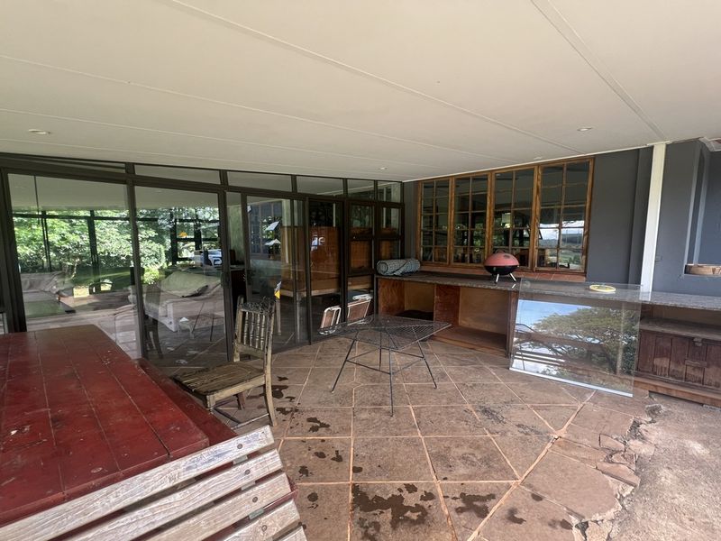 Covered patio area featuring a built-in stone-topped counter, large glass sliding doors, and tiled flooring, suitable for outdoor entertaining.