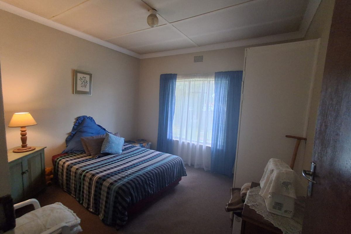 A standard bedroom featuring carpet flooring, a built-in wardrobe, and a large window allowing natural light.