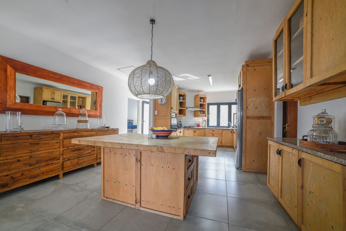 Spacious kitchen featuring custom timber cabinetry, a central wooden island, tiled flooring, and integrated storage solutions.