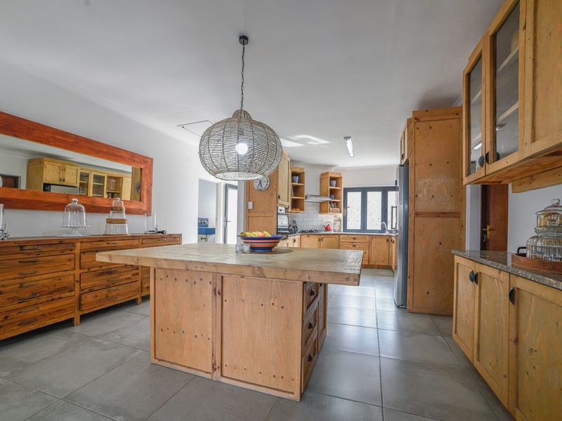 Spacious kitchen featuring custom timber cabinetry, a central wooden island, tiled flooring, and integrated storage solutions.