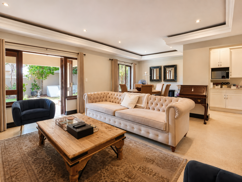Spacious open-plan living and dining area featuring recessed ceiling lighting, neutral tiled floors, and direct access to a private outdoor patio.