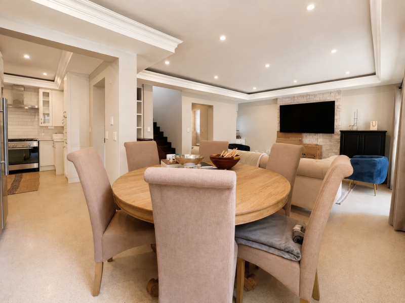 Spacious open-plan living and dining area featuring a modern kitchen with subway tile backsplash, stone fireplace feature wall, and recessed ceiling lighting.